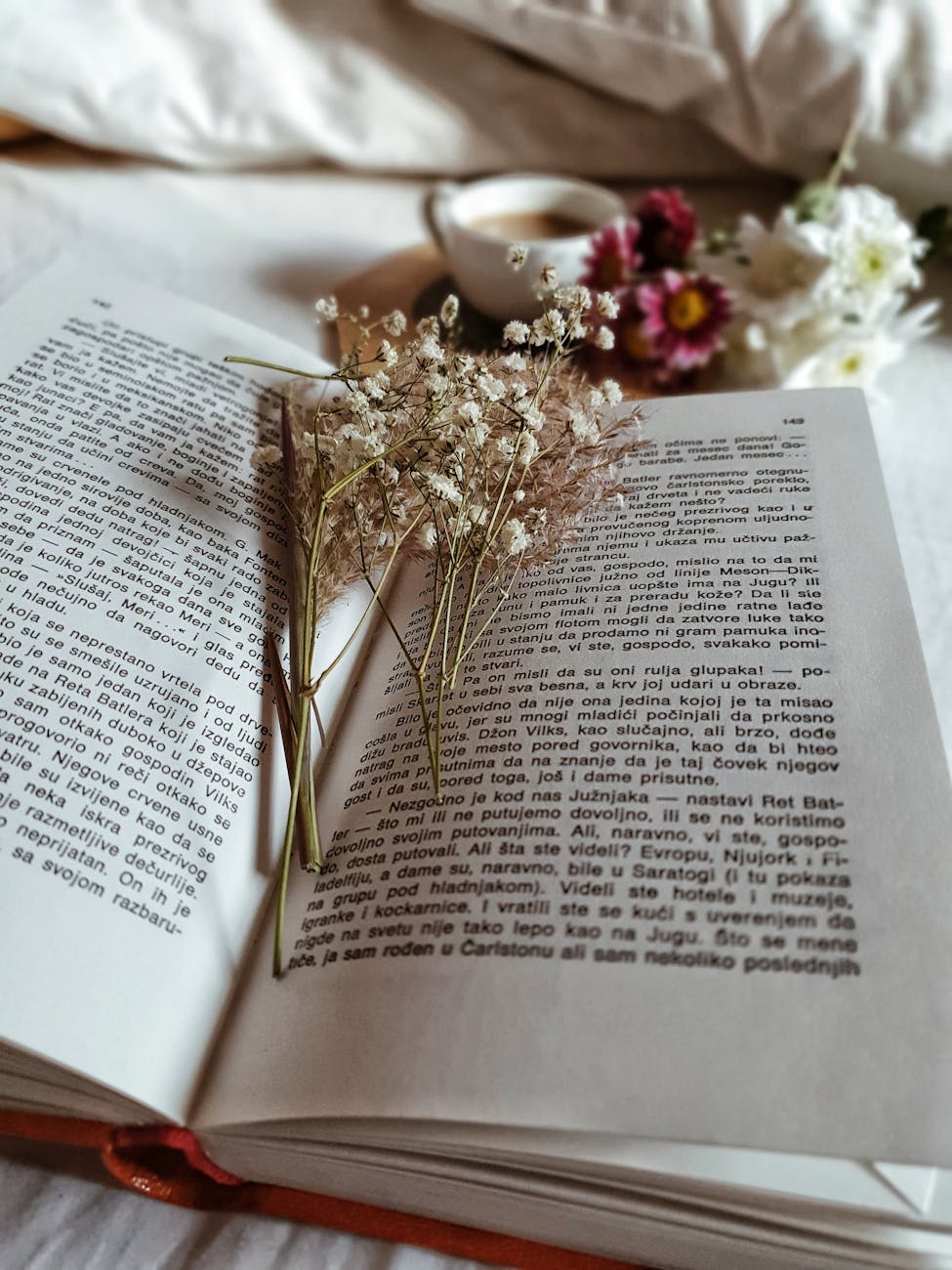 dried plants in opened book on cozy bed